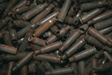 
A lot of used old, rusty brass cartridge cases from the machine. Empty carbine or rifle cartridges. Background of brass ammunition cartridges to illustrate armed conflict, war or shooting.
