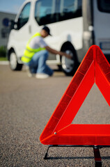 Red triangle and man near broken car outdoors