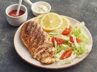 Fried chicken breast. Grilled chicken breast with vegetable salad and lemon