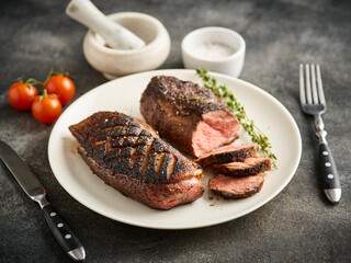 Juicy tasty fragrant roasted duck breast on a white plate with peppers and cherry tomatoes.