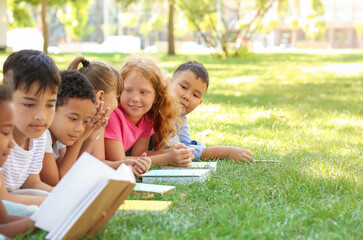 Cute little children reading books in park