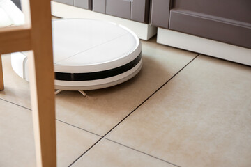 Modern robot vacuum cleaner on floor in kitchen