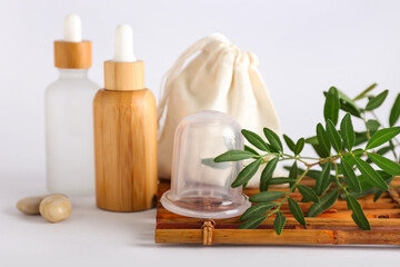 Vacuum jar for anti-cellulite massage and bottles of cosmetic products on white background