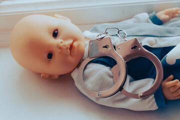 baby doll lies with handcuffs. child crime concept
