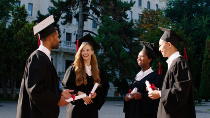 Graduation day in the college garden group of students graduates holding their diplomas and...