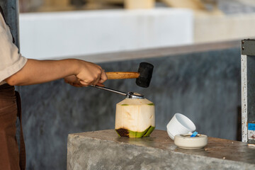 Woman opens a coconut with a hammer in cafe on island Koh Phangan, Thailand