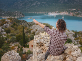 Travel and tourist attractions at Kekova island, Turkey. Man traveler explores ruins castle of Simena with view of sea bay and Kekova Island with famous flooded city. Tourist attractions in Turkey.