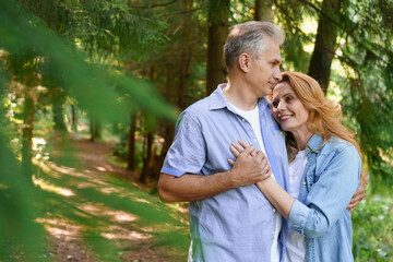 Happy old elderly caucasian couple smiling in park on sunny day cuddling, hugging senior couple relax in spring time. Lifestyle Health Care Elderly Retirement Love Couple Together in Trees Background