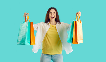 Crazy joyful woman with colorful packets shouts excited from her shopping at seasonal sales. Casual...