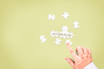 A businessman collects the words "Action plan" from puzzle pieces