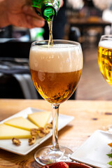 Lunch with cold beer in Spanish outdoor cafe, tapas bowl with green olives and Spanish cheese manchego with nuts