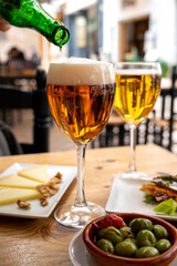 Lunch with cold beer in Spanish outdoor cafe, tapas bowl with green olives and Spanish cheese manchego with nuts