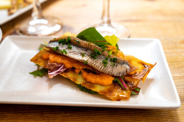 Spanish food, one tapas small piece of roasted bread cracker with vegetables puree and smoked sardine fish