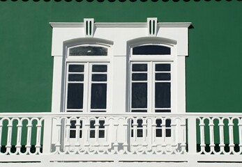 Traditional windows with balcony on a green wall
