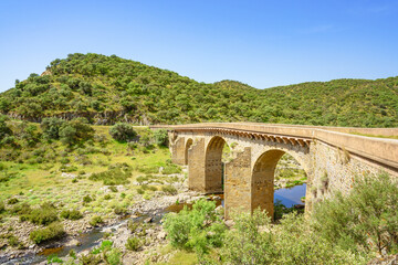 Fototapeta na wymiar An ancient arched bridge spans over Salor river in Extremadura, Spain