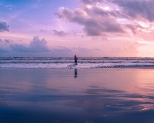 Fototapeta premium child enjoying the waves in the beach during sunset.
