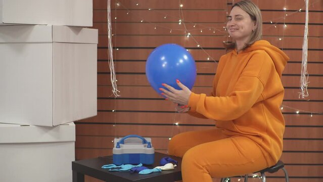 girl inflates a blue balloon