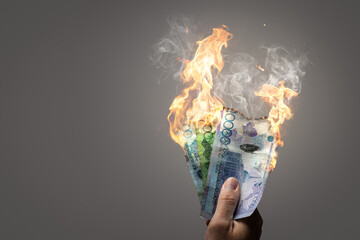 Burning Kazakh Tenge banknotes held by a hand