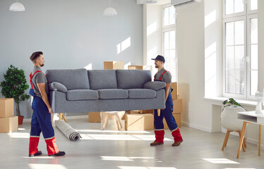 Loading service. Male loaders take sofa out of apartment while fulfilling order at moving service....