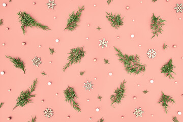 pastel festive Christmas or winter pattern made of natural fluffy green fir branches and wood snowflakes on soft pink background. Trendy simple minimal neutral xmas template. Top view flat lay style