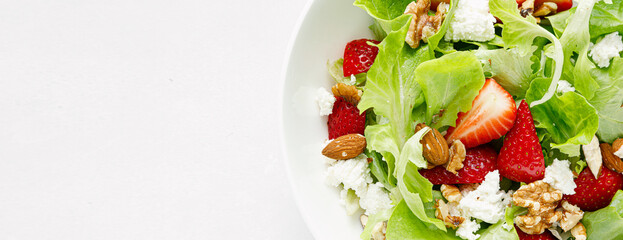 Strawberry and cottage cheese fresh fruit salad with walnut, almond and lettuce. Top view. Banner