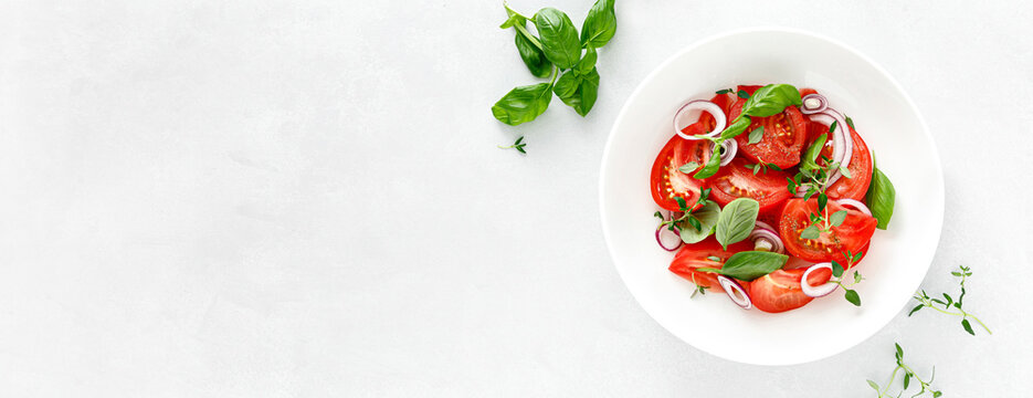 Salad with red ripe tomatoes, basil and olive oil. Top view. Banner