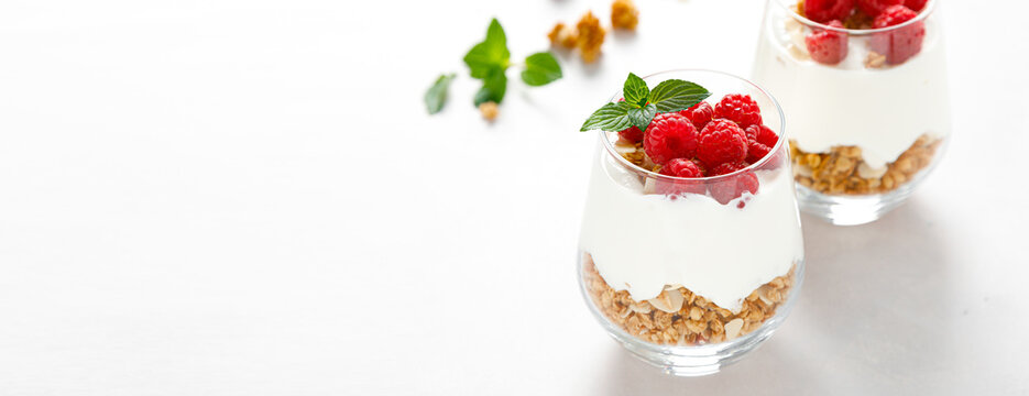 Granola with white plain yogurt and raspberry in a glass. Banner