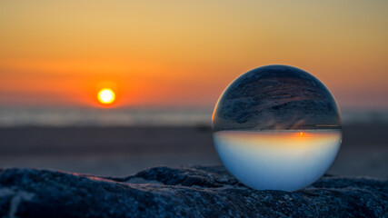 ein Sonnenuntergang der sich in einer Glaskugel spiegelt