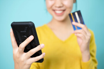 Young woman takes a photo of herself using a smartphone and credit card to pay online.
