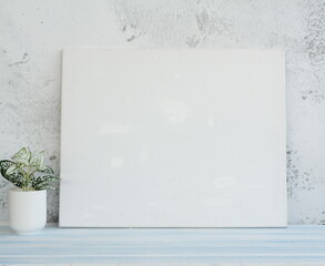 White canvas hanging on light blue wooden wall. Mockup, wall decor, blank canvas stretched on stretcher bar