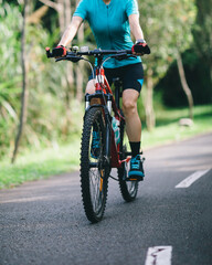 Fototapeta na wymiar Woman cycling on tropical park trail in summer