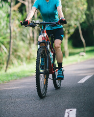 Fototapeta premium Woman cycling on tropical park trail in summer