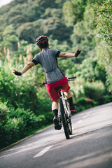 Woman feel free cycling on tropical park trail in summer