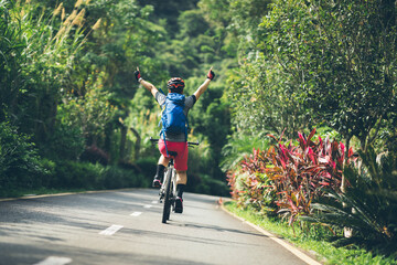 Woman feel free cycling on tropical park trail in summer