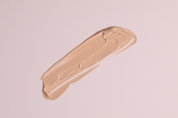 Smeared liquid beige make up foundation on pastel pink background. BB, CC cream foundation tonal smudge