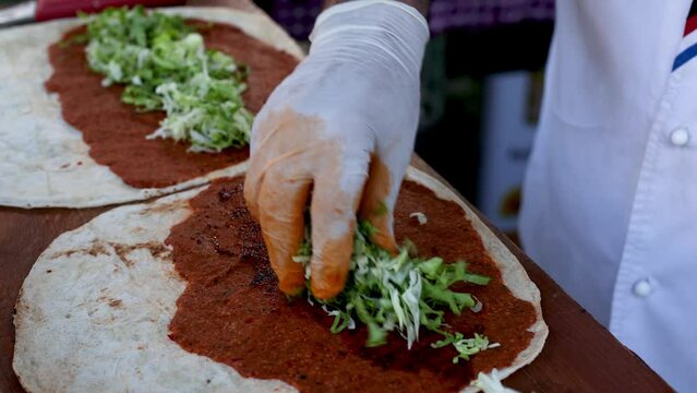 Cooking traditional turkish dish at street food festival, chef preparing lavash, bulgur and lettuce dish, turkish cuisine vegetarian dish, cig kofte