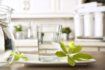 Glass of purified water and jug on kitchen bench closeup - obrazy, fototapety, plakaty