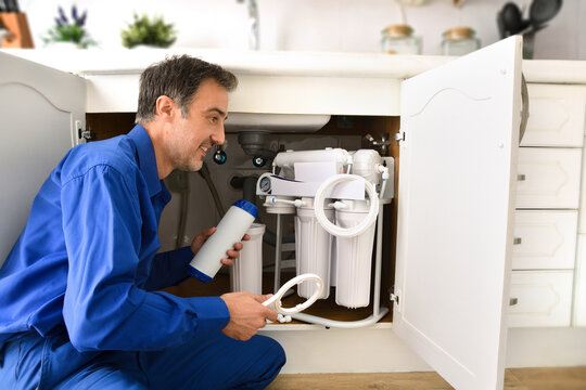 Technician Installing Reverse Osmosis Equipment Under The Sink