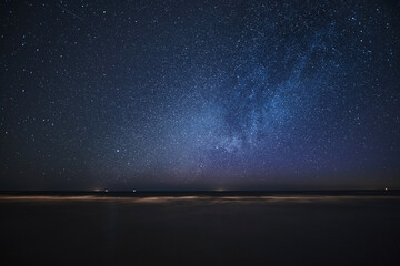 Milky Way galaxy on a sandy sea beach. Star watching during outdoor summer holidays on the seaside.