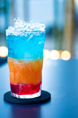 cocktail of blue, orange and red color, in glass glass and blurred background