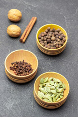 Cardamom, cloves and allspice in wooden bowls.