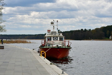 A view of a luxirious boat parked next to a small wooden marina, pier or platform with a metal...