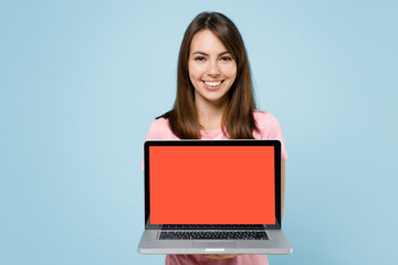 Young smiling freelancer happy caucasian woman 20s in pink t-shirt hold use work on laptop pc computer with blank screen workspace area isolated on pastel plain light blue background studio portrait