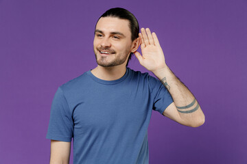 Young smiling curious happy fun nosy man 20s wearing basic blue t-shirt try to hear you overhear...