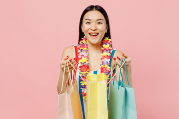 Fun young happy woman of Asian ethnicity in striped swimsuit hawaii lei hold show package bags with...