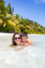 Mother and son in the water on a beach in the Maldives