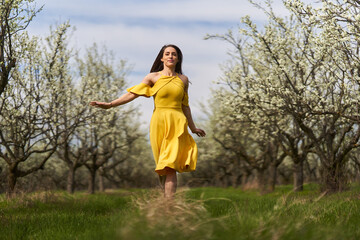 Naklejka na ściany i meble Happy woman in the blooming orchard