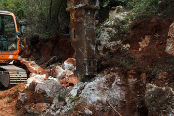 Excavator crusher machine breaks rocks to widen road