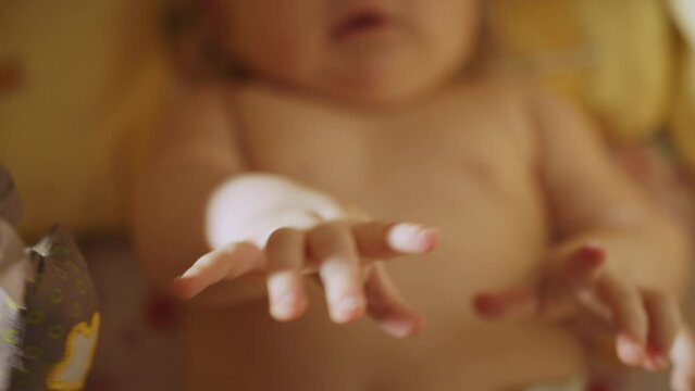 Baby care, first skills, learning to sit. A newborn baby lies in a crib and looks at a toy mobile. Child in the cradle. Playful Portrait of a Caucasian Neonate Toddler Looking at Rotating Toys