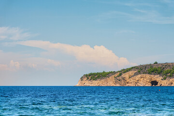 Fototapeta premium Beautiful blue sea with part of mountain coastline and cloudy sky